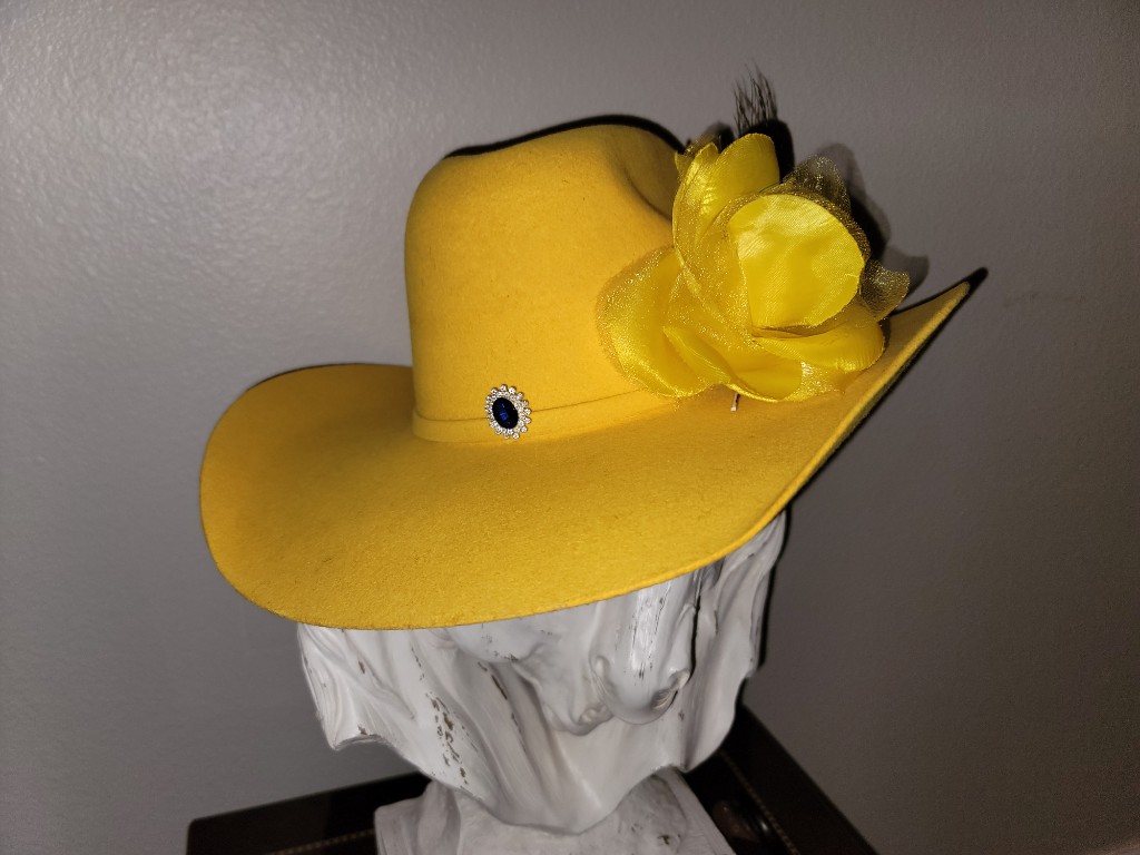 Western GQ luxury fashion — vibrant yellow felt hat with fabric flower and gemstone brooch on white bust